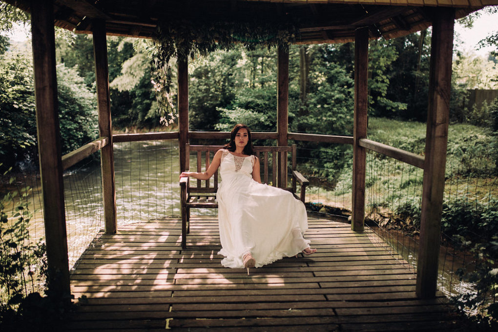 Plan large de la robe Blanche portée par une femme assise sur un banc dans un kiosque en bois