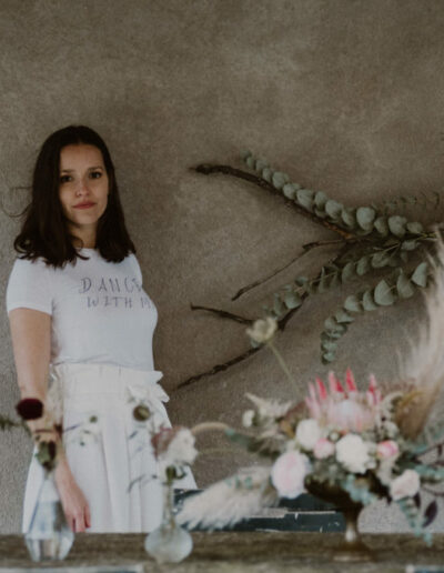 Photo du pantalon Emio avec des bouquets de fleurs autour, posés sur une table