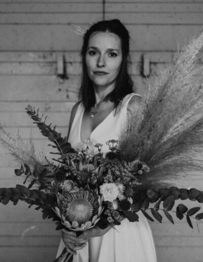 Photo en noir et blanc, plan taille, de la robe Irene portée avec un bouquet de fleurs séchées
