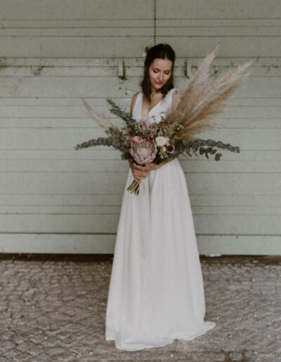 Plan large de la robe Irene portée avec un bouquet de fleurs séchées