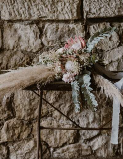 Photo du bouquet de fleurs séchées sur une table, devant un mur en pierre